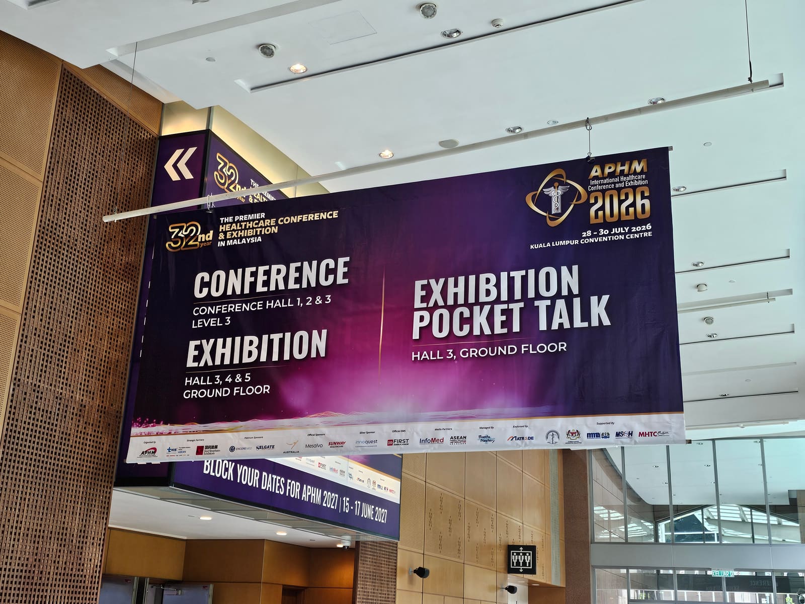 APHM 2026 wayfinding banner at KLCC listing conference and exhibition hall locations and the 28–30 July 2026 dates — MedicalMet